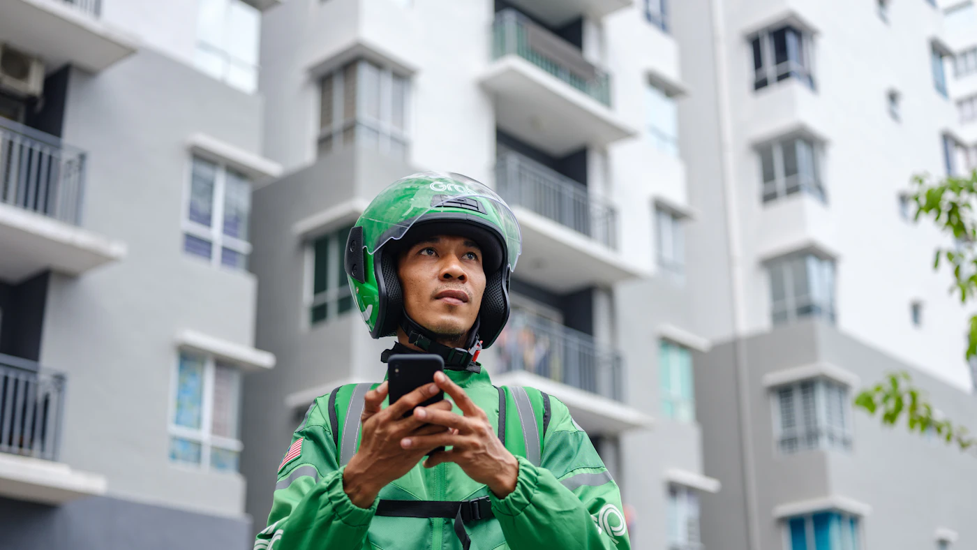 Un livreur casqué consulte son téléphone entre deux courses