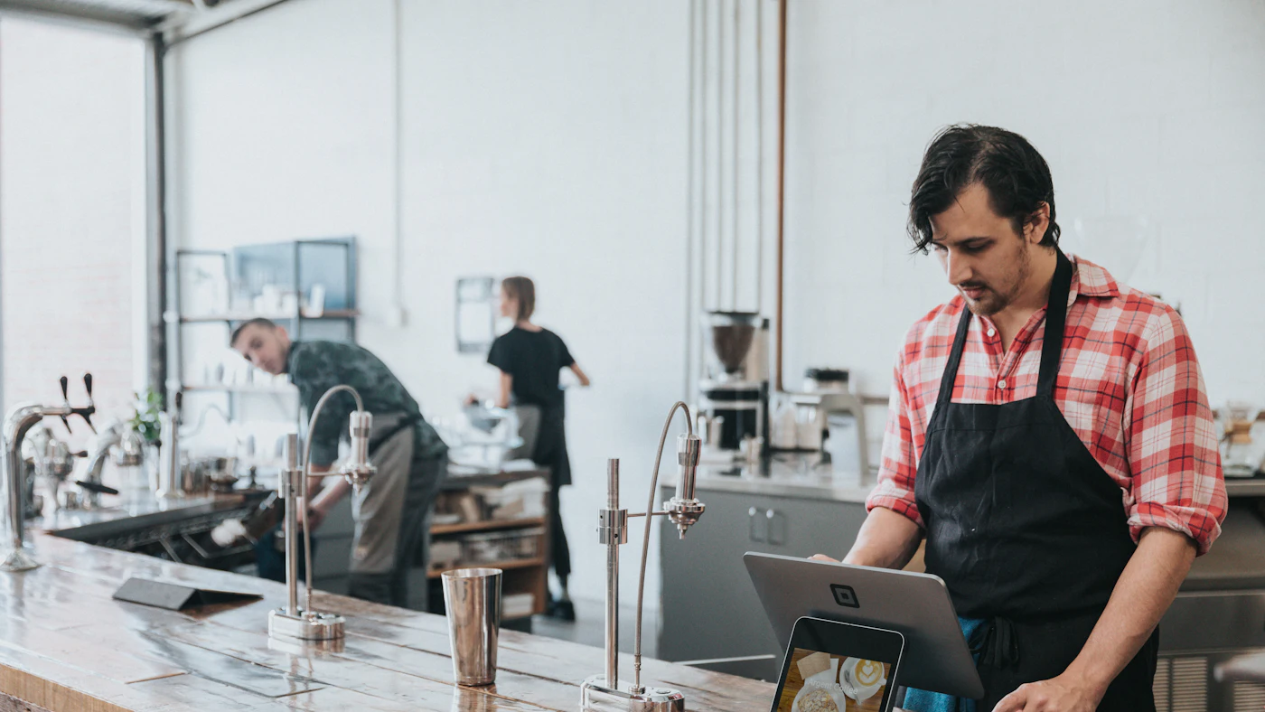 Un barista prend une commande sur sa tablette de caisse