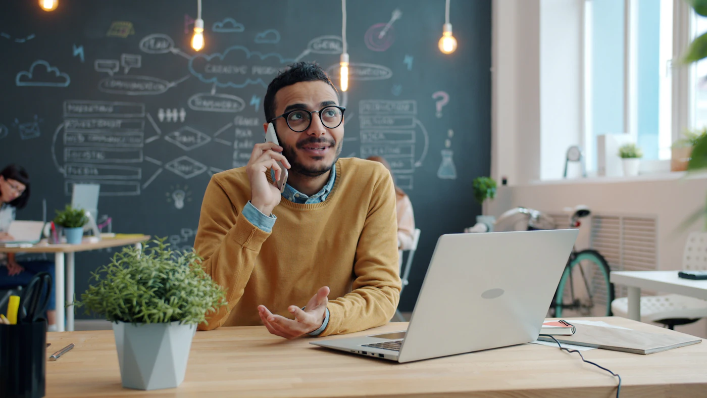 Un commercial au téléphone avec un prospect, laptop ouvert